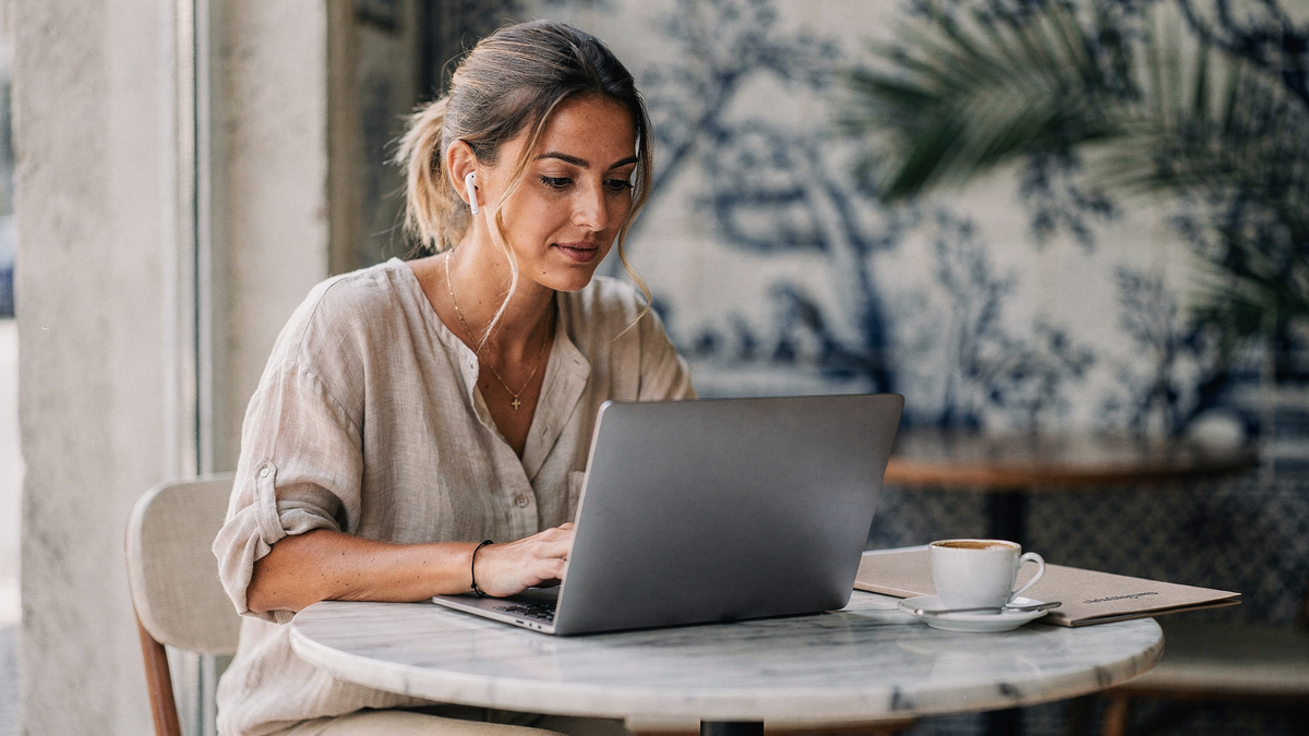 Freelancer kalkuliert am Laptop den Stundensatz mit Taschenrechner und Notizen