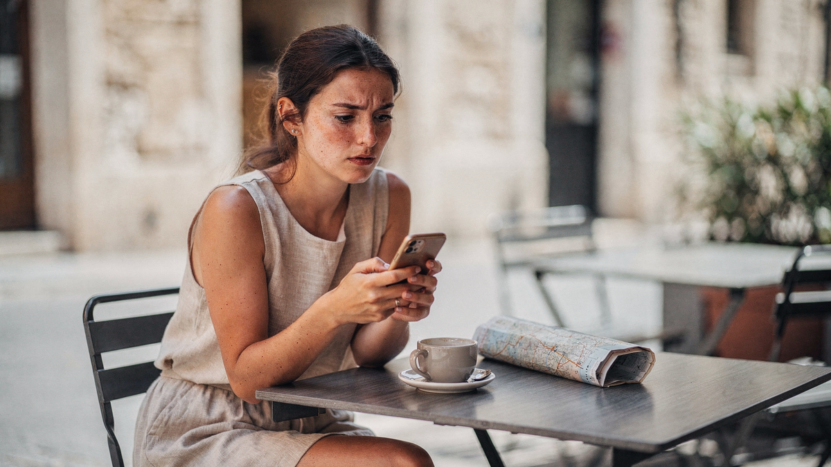 Reisende prüft Roaming-Kosten am Smartphone im Ausland — EU- und Drittland-Tarife 2026